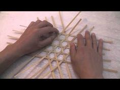 two hands are working on an object made out of sticks