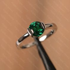 It is a lab emerald ring. The main stone is 7 mm*7 mm round cut.weight about 1.30 carats.The basic metal is sterling silver and plated with rhodium/14k white  gold/14k rose gold/14k yellow goldYou can also go to my shop Home for more elegant rings: https://www.etsy.com/shop/godjewelry?ref=hdr_shop_menu Customization is always welcome and please feel free to contact with me if you have any design ideas! Classic Round Emerald Ring With Tension Setting, Classic Emerald Ring With Round Stone For Anniversary, Classic Round Emerald Promise Ring, Emerald Round Band Ring For May Birthstone Anniversary, May Birthstone Solitaire Ring With Round Cut, White Gold Solitaire Ring For May Birthstone, May Birthstone Jewelry With Tension Setting For Anniversary, Classic Silver Emerald Birthstone Ring, Sterling Silver Emerald Ring With Round Stone