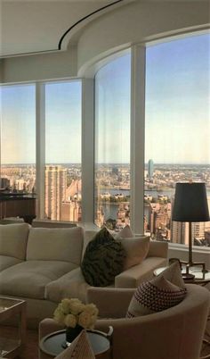 a living room filled with furniture and large windows overlooking a cityscape in the distance