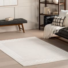 a living room with a black leather couch and white rug