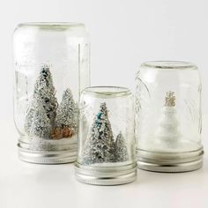 three glass jars filled with snow covered trees