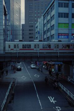 a train traveling over a city street next to tall buildings