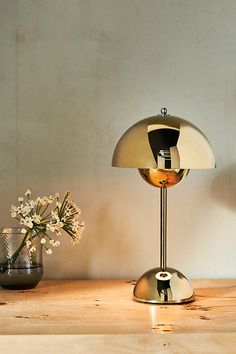 a table lamp sitting on top of a wooden table next to a vase with flowers