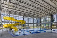 a large indoor swimming pool with yellow slides