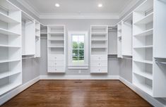 an empty walk in closet with lots of white shelving and drawers on the walls