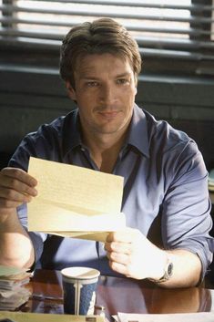 a man sitting at a table holding a piece of paper