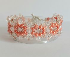 This lovely beaded bracelet has a vintage look to it and is made of small orange pearls, silver-lined crystal seed beads, black crystals, and silver/clear oval beads.. The bracelet is approx 2.4 cm/ 1" wide, fastens with a silver tone toggle clasp. Will fit a 19.1cm/7.5" wrist. Handmade Pearl Crystal Bracelet As Gift, Handmade Pearl Crystal Bracelet For Gift, Handmade Pearl Crystal Bracelet Gift, Handmade Peach Bracelet Gift, Beaded Crystal Pearl Bracelet, Handmade Pearl Beaded Bracelets For Party, Handmade Peach Beaded Bracelets As Gift, Handmade Peach Beaded Bracelets For Gift, Elegant Coral Beaded Bracelets