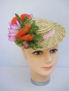 a white mannequin head wearing a straw hat with carrots and flowers on it