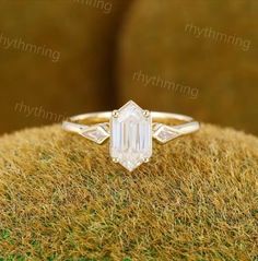 an emerald cut diamond ring on top of grass