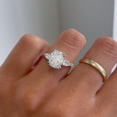 a woman's hand with a diamond ring on top of her finger and an engagement band