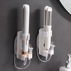 two white electrical plugs attached to a wall next to a mirror and sink in a bathroom