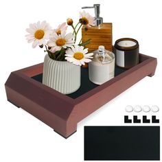 a wooden tray with flowers, candles and other items on it in front of a white background