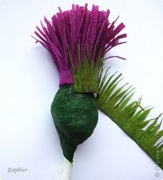 a green and purple flower on a white surface