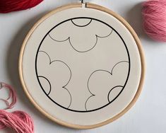 a close up of a cross stitch pattern on a wooden hoop with yarn and scissors