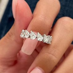 a woman's hand holding an engagement ring with five pear shaped diamonds on it