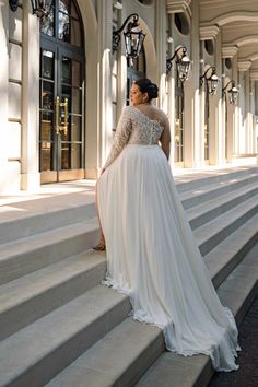 a woman in a wedding dress standing on the steps outside an old building with columns