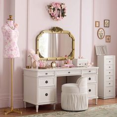 a dressing table with a mirror, stool and dress on it in a pink room