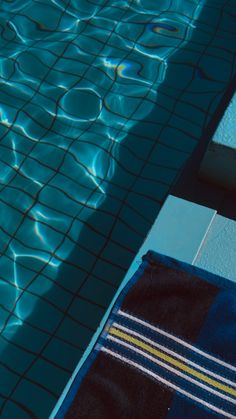 a towel sitting on the edge of a swimming pool next to a blue tiled floor