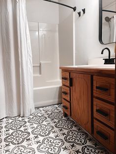 a bathroom with black and white tile flooring next to a bathtub, sink and shower