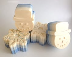 three soaps with frosting on them sitting next to each other and one is shaped like a snowman