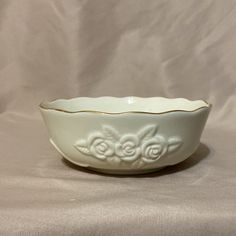 a white bowl sitting on top of a table next to a white cloth covered wall