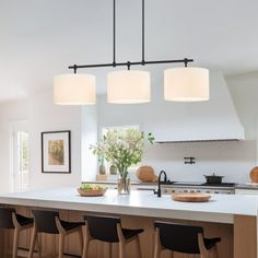 a kitchen with an island and four lights hanging from it's ceiling over the counter