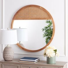 a round mirror sitting on top of a dresser next to a lamp