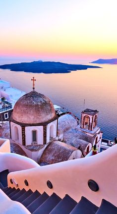 an aerial view of a church in the snow at sunset, with water and mountains in the background