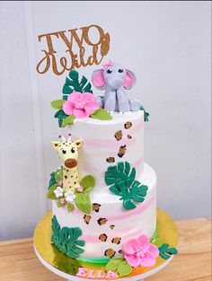 a three tiered cake with an elephant and giraffe topper on it