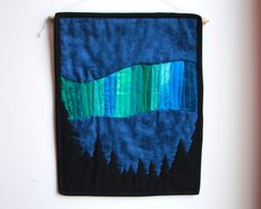 a blue and green piece of art hanging on a wall