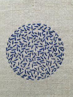 an embroidered circle with small blue dots on the inside of it, in front of a white background