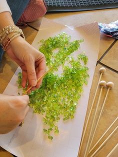 a person cutting up green vegetables with chopsticks on the table next to them