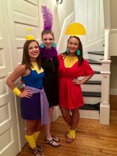 three women dressed in costumes standing next to each other on a wooden floor near stairs