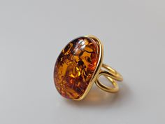 Amber ring. Brown Orange Baltic Amber gemstone ring. Certificated gold plalted Sterling silver 925 with stamps - hallmarks. Big nice stunning ring. Adjustable size. Very big and stunning amber gemstone ring.  weight 11 gr GOLD plated sterling silver 925 ring.  Stone size-  2,7x2  cm This item was made of natural Baltic Amber. All the amber used in my jewelry is collected in my home country Lithuania.  I sell only genuine,  real, not pressed, authentic, natural Baltic Amber. Item may have natural Elegant Gold Crystal Ring With Polished Finish, Gold Dome Ring With Cabochon For Formal Events, Gold Crystal Ring With Polished Finish For Formal Occasions, Formal Yellow Gold Crystal Ring With Polished Finish, Formal Amber Rings In Fine Jewelry Style, Amber Rings For Formal Occasions, Fine Jewelry, Amber Rings For Formal Occasions In Fine Jewelry Style, Luxury Amber Rings For Formal Occasions, Elegant Amber Cabochon Ring