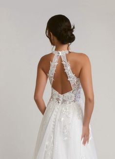 a woman in a white wedding dress is looking down at the back of her gown