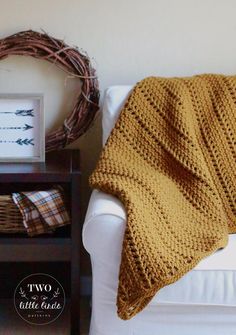 a crocheted blanket sitting on top of a white couch next to a wreath