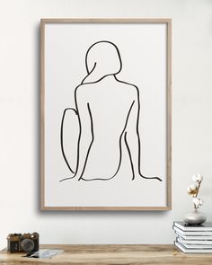 a line drawing of a woman's torso on a white wall above a wooden table