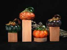 three glass pumpkins sitting on top of wooden blocks