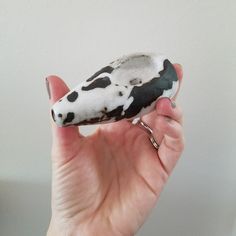 a hand holding a black and white object in it's left hand, with the tip of its thumb out