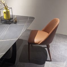 a brown chair sitting on top of a black table next to a vase with flowers