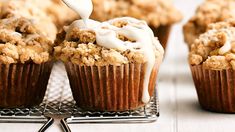 some muffins on a cooling rack with icing being drizzled over them