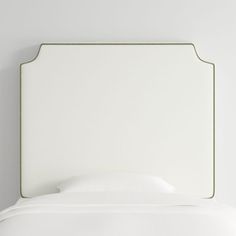 the headboard of a bed with white sheets and pillows