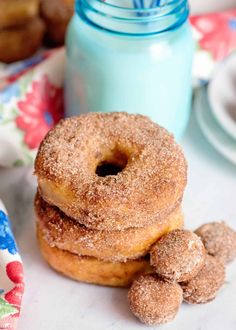 three sugar donuts stacked on top of each other next to a jar of milk