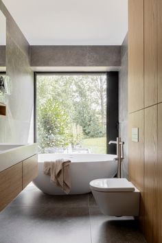 a bathroom with a tub, sink and large window in the corner that overlooks trees