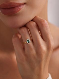 a woman wearing an emerald and diamond ring