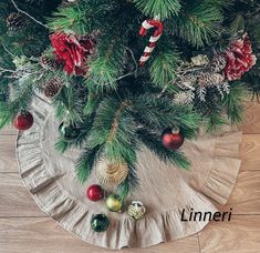 a christmas tree skirt with ornaments and candy canes on the top, sitting on a wooden floor