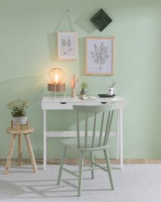 a white desk and chair in a room with green walls, two pictures on the wall