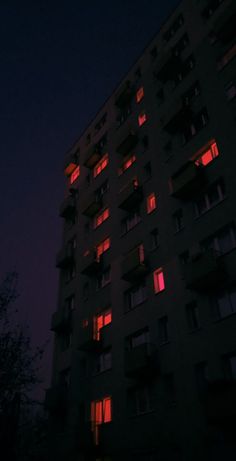 an apartment building is lit up with red light at the top and bottom windows,