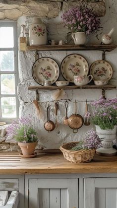 an old fashioned kitchen with pots and pans on the wall, flowers in vases