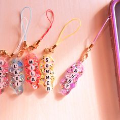 four keychains with words on them sitting next to a cell phone and case